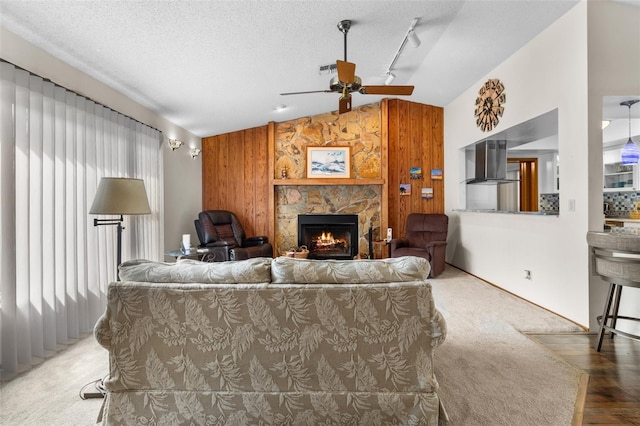 living room with vaulted ceiling, a wealth of natural light, wood walls, and a stone fireplace