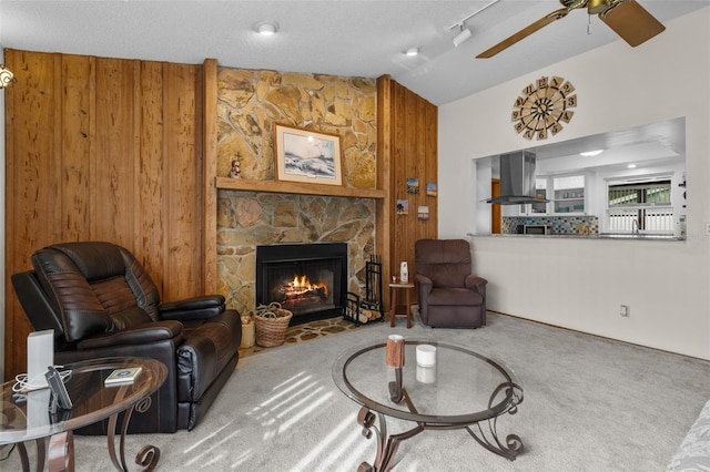 living room with a textured ceiling, carpet floors, a fireplace, wooden walls, and vaulted ceiling