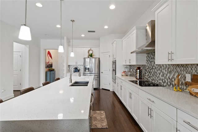 kitchen with stainless steel appliances, a spacious island, decorative light fixtures, wall chimney exhaust hood, and white cabinets