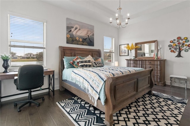 bedroom with a notable chandelier, dark hardwood / wood-style floors, a tray ceiling, and multiple windows