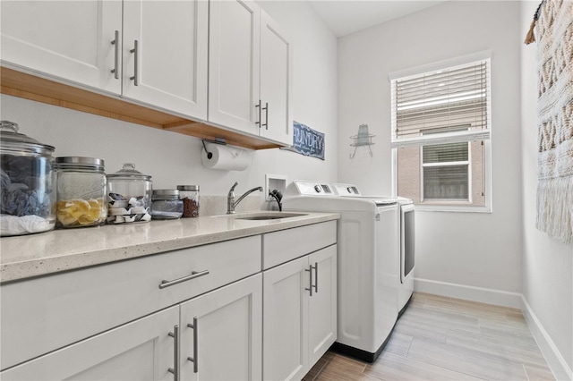 laundry room with cabinets, washer and clothes dryer, and sink