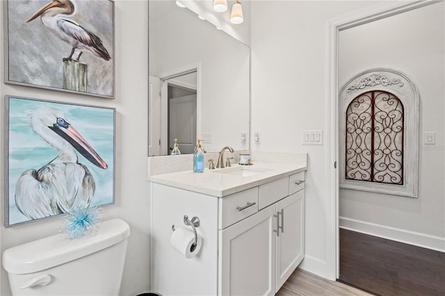 bathroom with toilet, hardwood / wood-style floors, and vanity