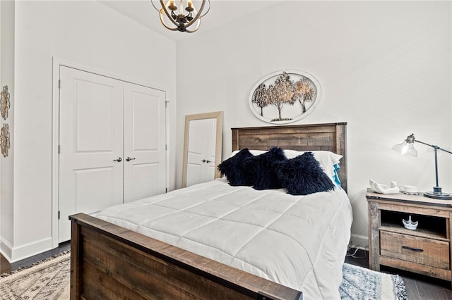 bedroom with lofted ceiling, a closet, dark hardwood / wood-style floors, and an inviting chandelier