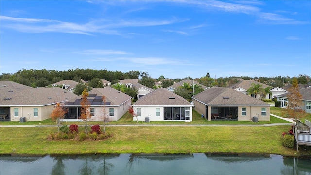 rear view of house featuring a sunroom, a water view, and a yard