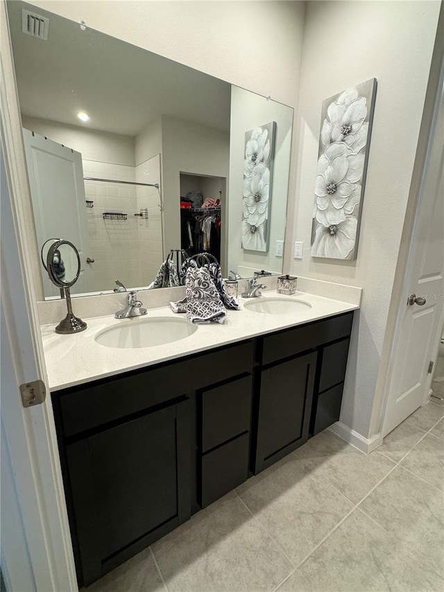 bathroom with tile patterned flooring, tiled shower, and vanity