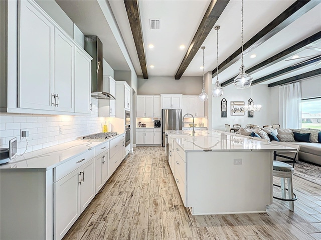 kitchen featuring white cabinetry, beamed ceiling, and wall chimney exhaust hood