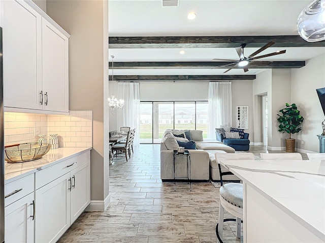 living room featuring ceiling fan with notable chandelier and beam ceiling