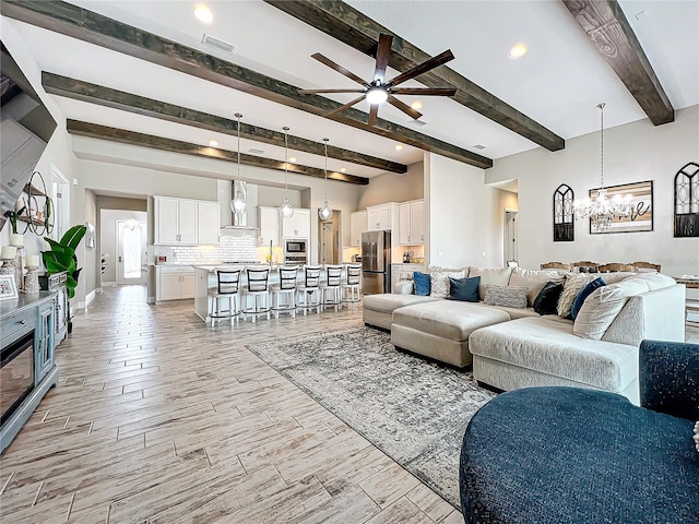 living room featuring ceiling fan with notable chandelier and beam ceiling