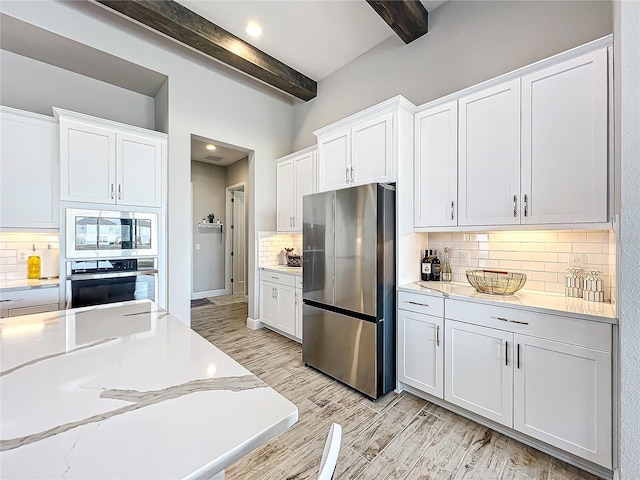 13028 Homestead Ln, Parrish, FL 34219 - kitchen with appliances with stainless steel finishes, beam ceiling, backsplash, light wood-style flooring, and white cabinetry