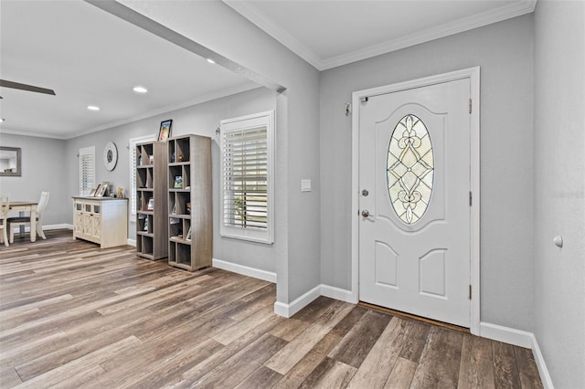 foyer entrance with ornamental molding, ceiling fan, and wood-type flooring