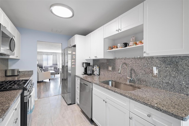 kitchen featuring white cabinets, sink, dark stone countertops, tasteful backsplash, and stainless steel appliances