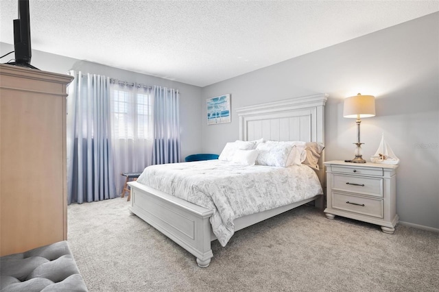 bedroom with light colored carpet and a textured ceiling