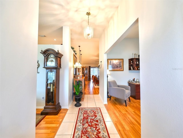 entryway featuring baseboards, a notable chandelier, and light wood-style flooring