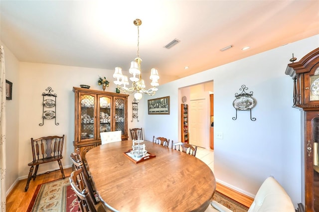 dining area with light wood finished floors, visible vents, baseboards, and an inviting chandelier