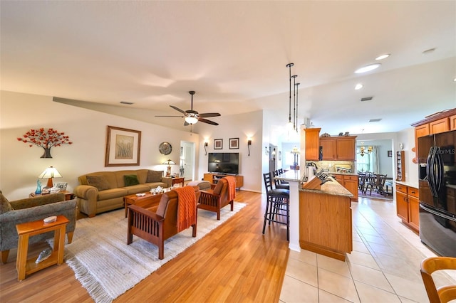 living area featuring light tile patterned floors, visible vents, lofted ceiling, and a ceiling fan