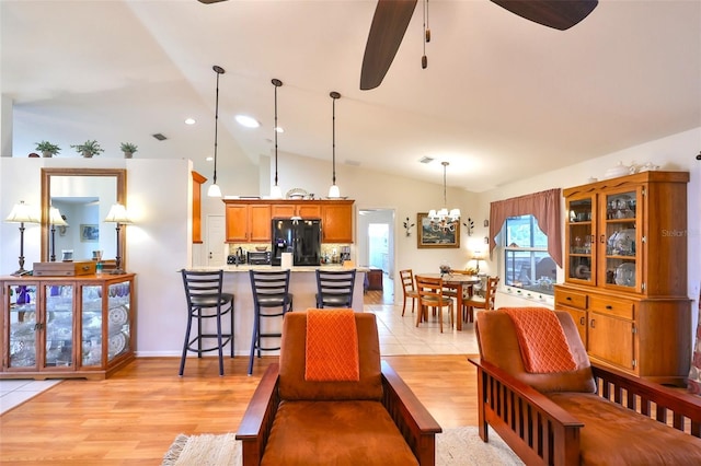 living area with light wood finished floors, visible vents, vaulted ceiling, recessed lighting, and ceiling fan with notable chandelier