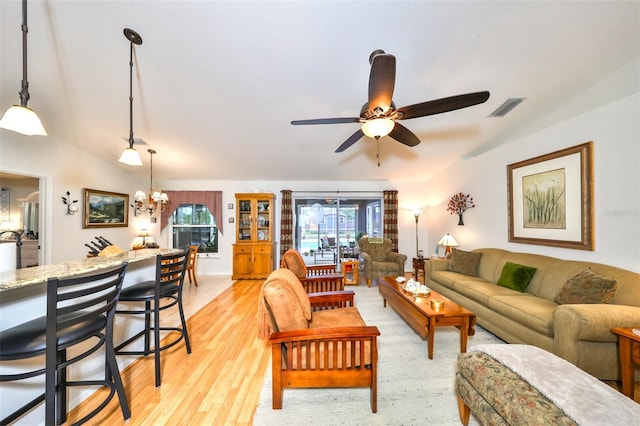 living room with visible vents, light wood-style flooring, and ceiling fan with notable chandelier