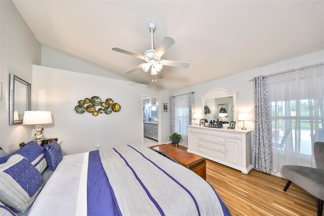 bedroom featuring light wood-type flooring, connected bathroom, a ceiling fan, and vaulted ceiling