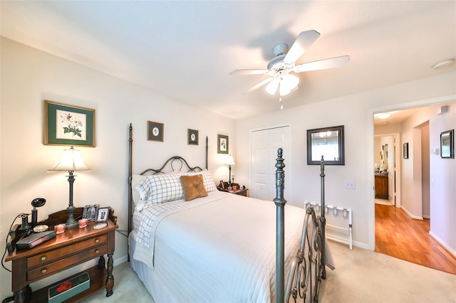 bedroom with a closet, baseboards, light colored carpet, and a ceiling fan