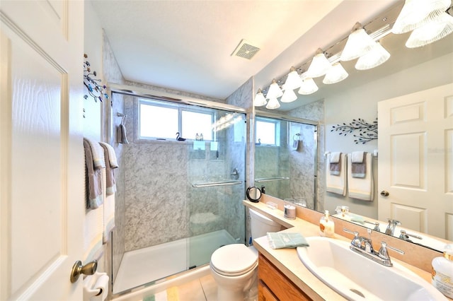 full bathroom featuring vanity, visible vents, a shower stall, tile patterned floors, and toilet