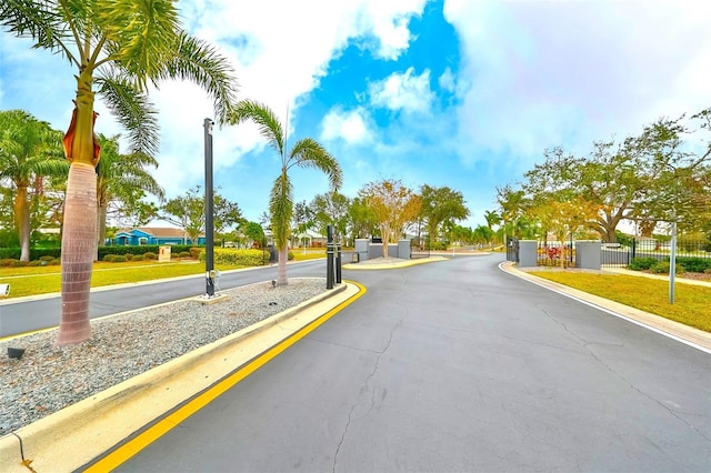 view of road with a gate, curbs, sidewalks, and a gated entry