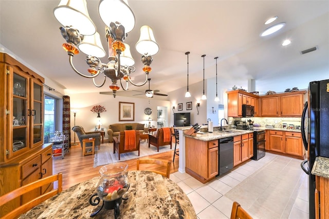 kitchen featuring visible vents, light stone countertops, open floor plan, black appliances, and a sink