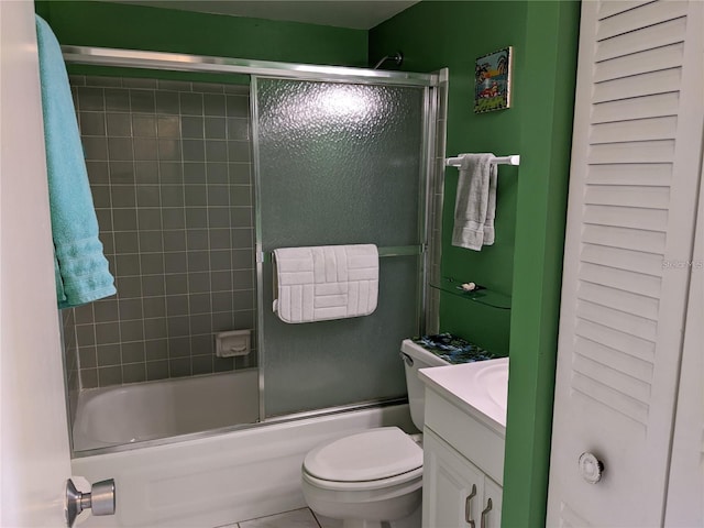 full bathroom with combined bath / shower with glass door, tile patterned flooring, vanity, and toilet