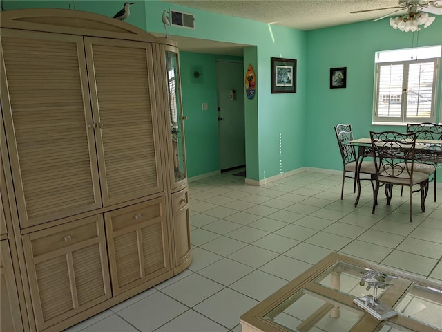 dining room featuring a textured ceiling, ceiling fan, and light tile patterned floors