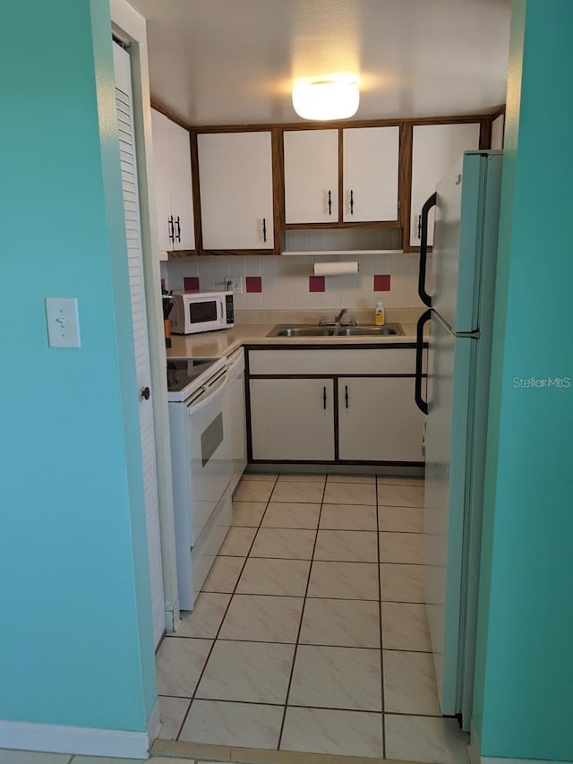 kitchen featuring white appliances, light tile patterned floors, backsplash, white cabinetry, and sink