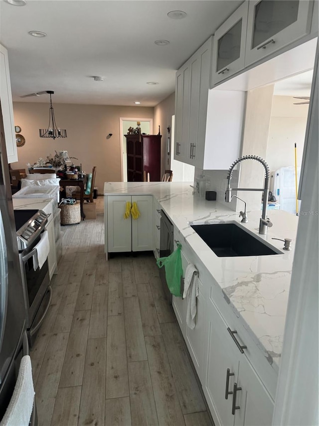 kitchen with white cabinetry, sink, pendant lighting, and kitchen peninsula