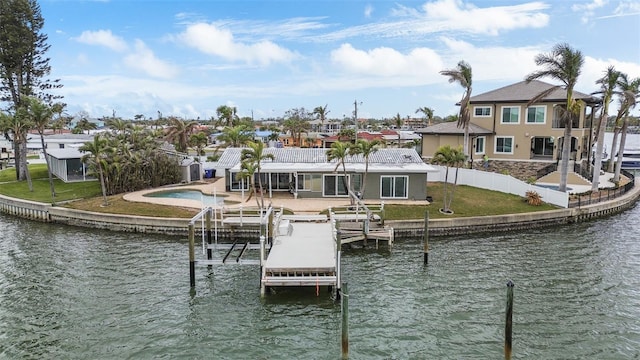 view of dock with a yard, boat lift, a water view, a patio area, and a residential view