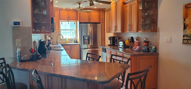 kitchen with kitchen peninsula, stainless steel fridge with ice dispenser, decorative backsplash, a breakfast bar area, and ceiling fan