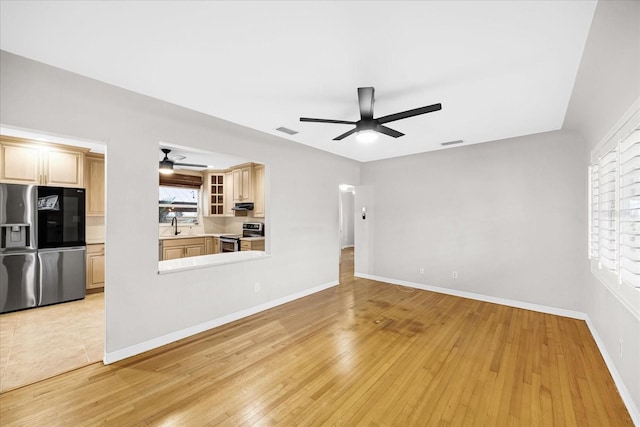 unfurnished living room with light hardwood / wood-style floors, ceiling fan, and sink