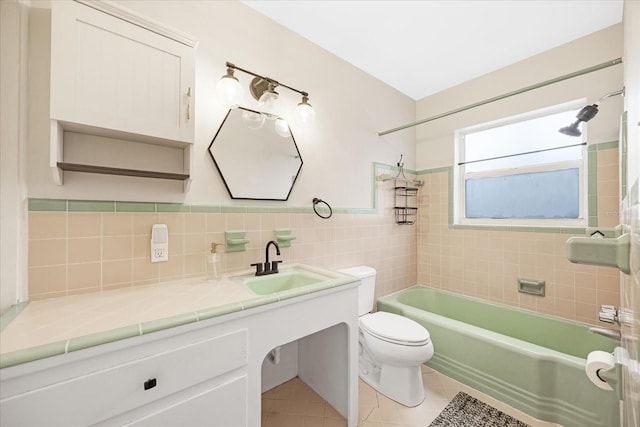 full bathroom featuring tile patterned floors, toilet, vanity, tile walls, and tiled shower / bath