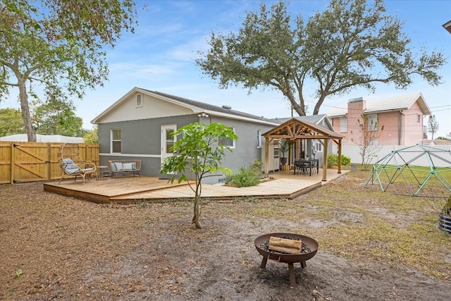 back of property with a fire pit, a gazebo, and a deck