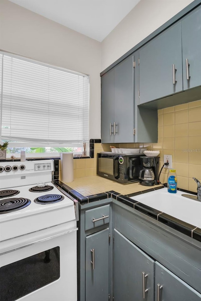 kitchen featuring a wealth of natural light, white electric range oven, gray cabinetry, and tasteful backsplash