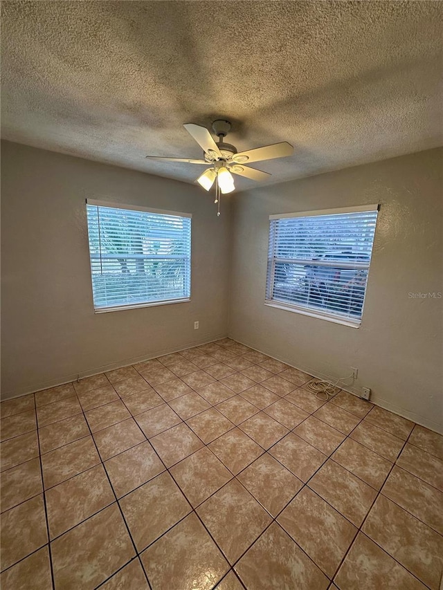 spare room featuring light tile patterned floors, a textured ceiling, and ceiling fan