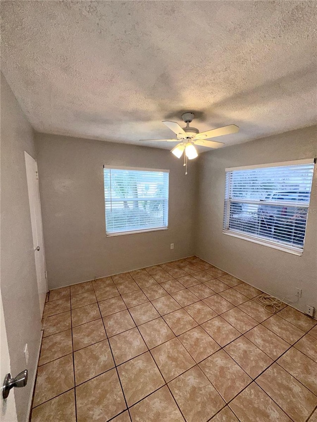 tiled empty room with a textured ceiling and ceiling fan