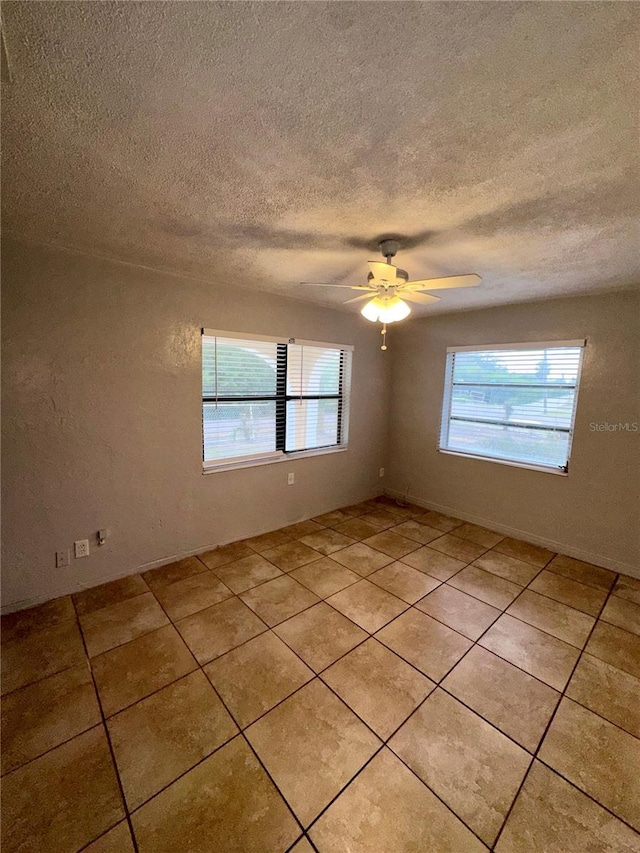 tiled spare room with ceiling fan, a healthy amount of sunlight, and a textured ceiling