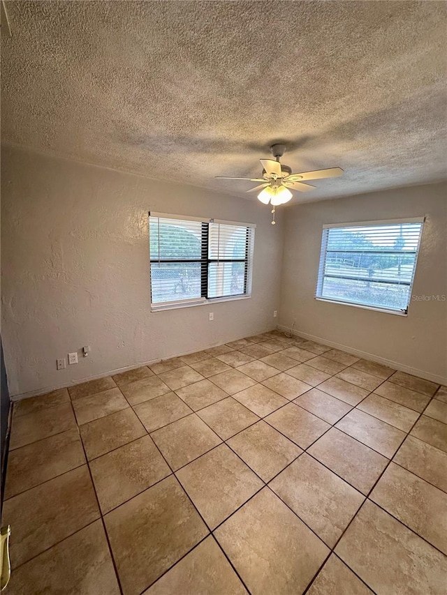 tiled spare room featuring ceiling fan, plenty of natural light, and a textured ceiling