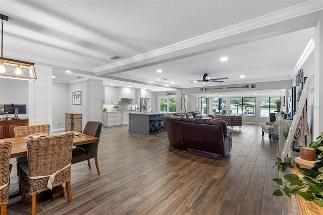 living room with a textured ceiling, ceiling fan, and crown molding