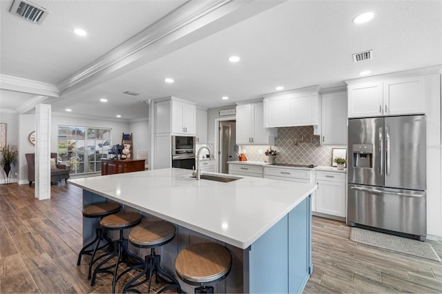 kitchen featuring crown molding, stainless steel refrigerator with ice dispenser, a spacious island, sink, and white cabinetry