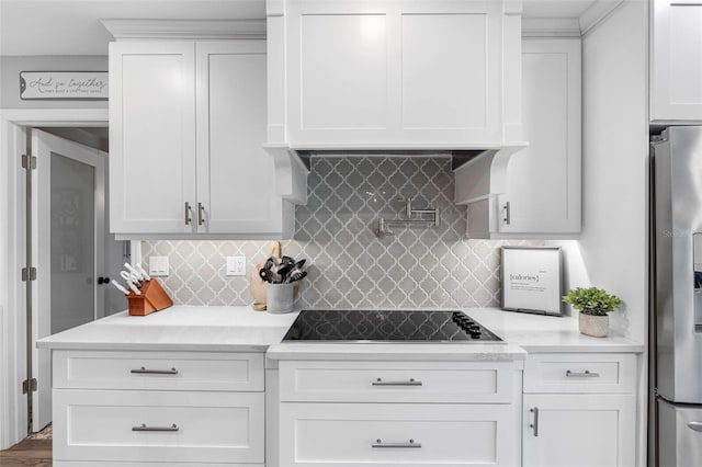 kitchen featuring white cabinets, stainless steel fridge with ice dispenser, black electric stovetop, and tasteful backsplash