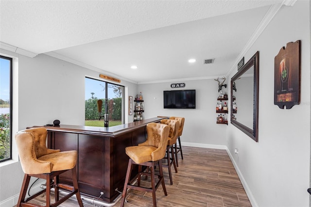 bar with hardwood / wood-style floors, ornamental molding, and plenty of natural light