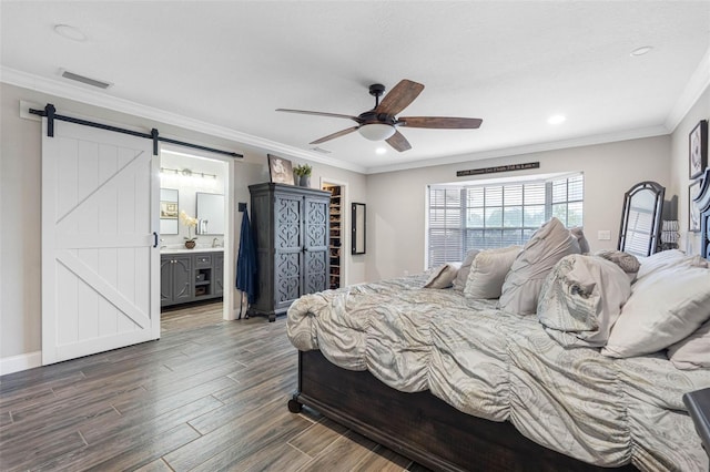 bedroom featuring ornamental molding, ensuite bath, ceiling fan, and a barn door