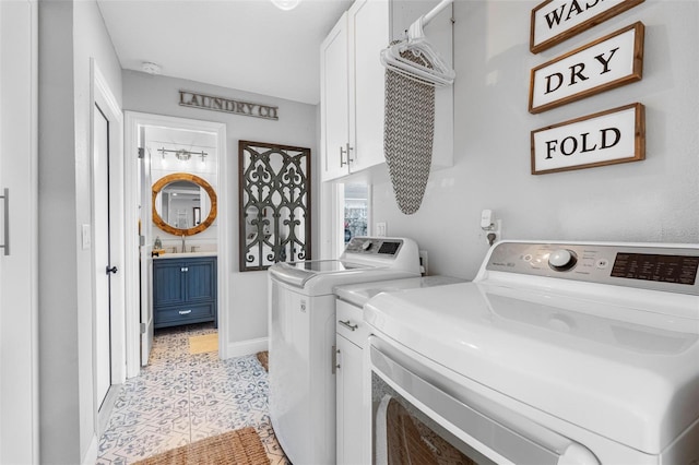 laundry area featuring washer and dryer, light tile patterned floors, and cabinets