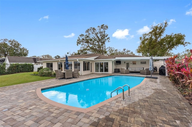 view of pool with a patio, a lawn, and an outdoor living space