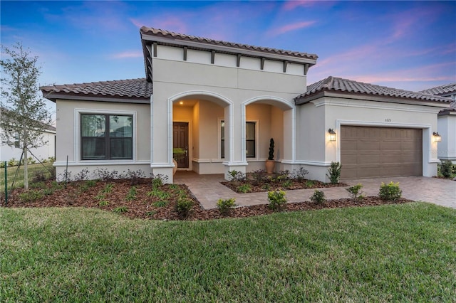 mediterranean / spanish house featuring a garage and a yard