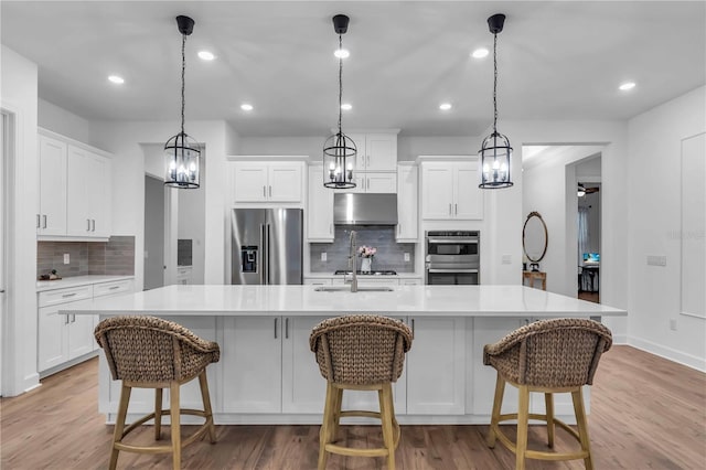 kitchen featuring decorative backsplash, white cabinets, appliances with stainless steel finishes, and a large island