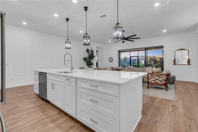 kitchen with sink, white cabinets, pendant lighting, and a center island with sink